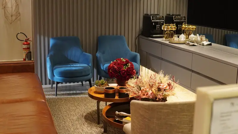 Sala de espera com poltronas azuis e flores